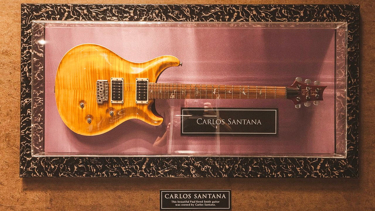Guitarra Paul Reed Smith cor de mel em vitrine com plaquinha de Carlos Santana